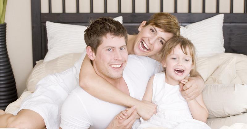 Glückliches Paar mit Kind im Bett des Liegestudio Sonnleitner