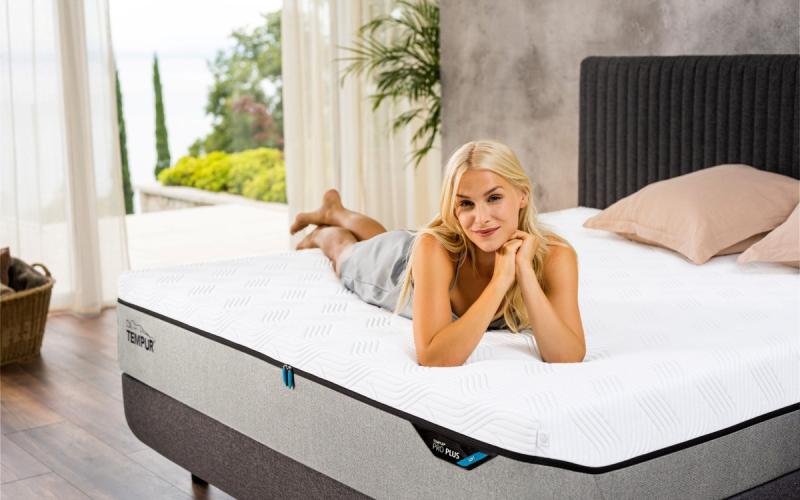Frau liegt auf einer TEMPUR PRO Plus Matratze in einem hellen Schlafzimmer